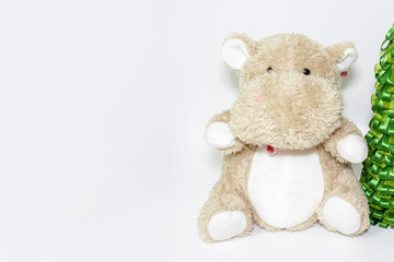Cute teddy hippo, soft toy with christmas tree on white background with copy space, holiday for kids concept