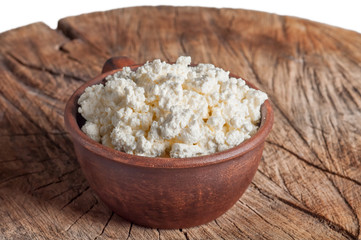 cottage cheese in a clay cup on an old wooden background