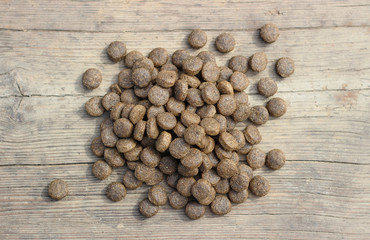 Dry food for any animals in granules on a wooden table.