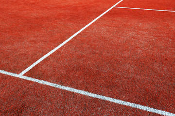 Part of empty used red tennis court playground surface with white lines closeup