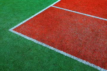 Part of empty used red tennis court playground surface with white lines closeup