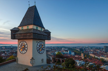 Cityscape of Graz and the famous clock tower (Grazer Uhrturm) on Shlossberg hill, Graz, Styria region, Austria, in autumn, at sunrise