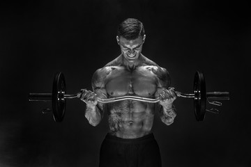 Fototapeta na wymiar Studio portrait of topless bodybuilder performing biceps exercise with concentrated face over black background with smoke. Cutout. Very brawny guy bodybuilder.