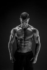 Fototapeta na wymiar Very brawny guy bodybuilder posing. Beautiful sporty guy male power. Fitness muscled man in studio. Dark background.