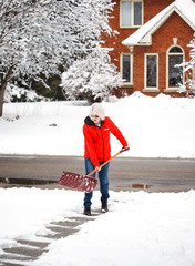 Young man with snow shovel cleans sidewalks in winter. Canada