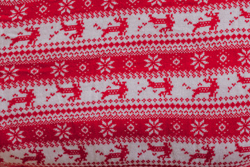 Real red knitted background with white Christmas deer and snowflakes