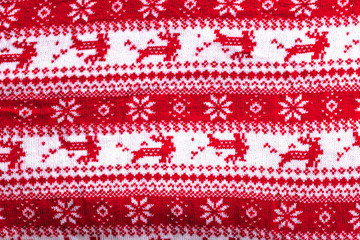 Real red knitted background with white Christmas deer and snowflakes