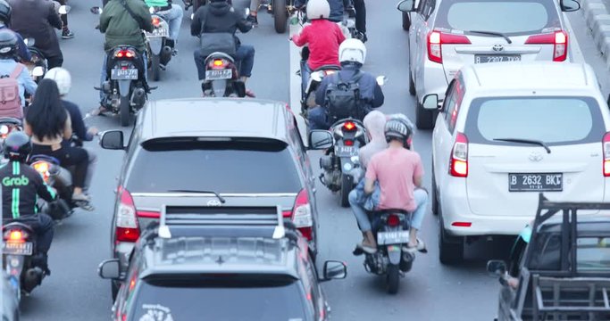 JAKARTA, Indonesia - November 27, 2019: Aerial landscape of numerous motorcycles and cars moving in traffic jam on rush hour at highway. Shot in 4k resolution from a drone