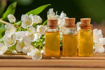 Essence of flowers on wooden background in beautiful glass jar