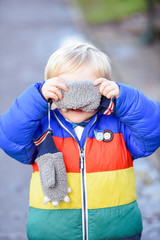 Naklejka premium Hide and seek The boy is playing outside in outdoor clothing he is covering face and hiding while looking at the camera