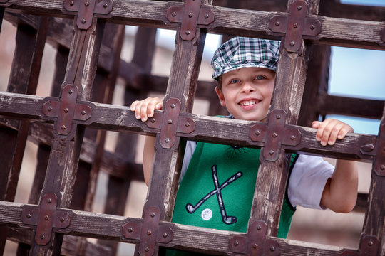 Young boy is inside a cage hanging down pose for fun at a middle age festival
