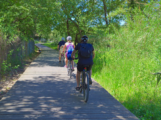 Obraz premium Family cycling on a wooden path thoroght green forest in Crete, Greece