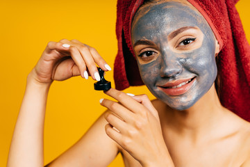 a girl with a black cosmetic mask on her face holds a black chess pawn in her hand. background...