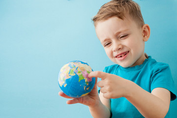 Little boy holding a globe on blue background