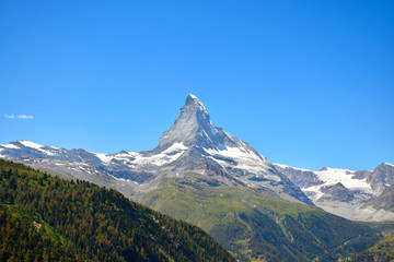 Fototapeta premium Gorgeous Matterhorn with a green and orange forest and a clear blue sky, Zermatt, Switzerland