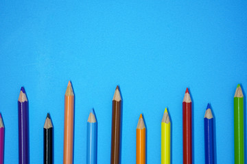 Crayons and pencil isolated on blue paper background with copy space