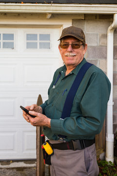 Handsome Home Inspector Poses In Front Of A Garage, Smiling. 