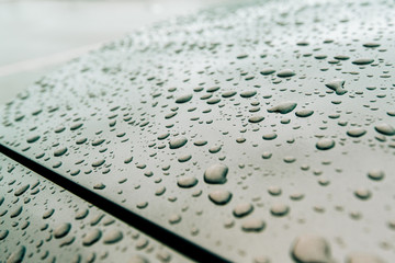 Macro close-up of multiple water drops on car new metallic paint - straight lines green color tones