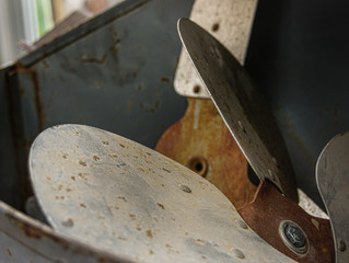Close up image of rusted metal propellers in a bin
