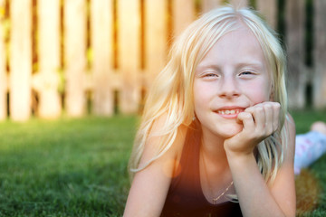 Fototapeta premium beautiful blonde smiling girl lying on the grass on a summer day