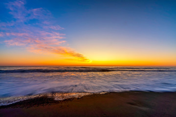 Fototapeta na wymiar Sunset on the Beach with Waves in Ocean 