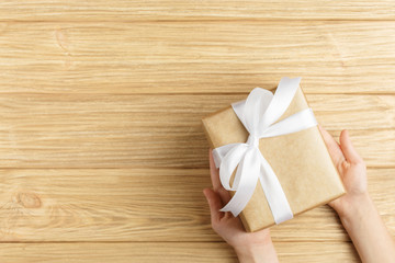 gift box in the hands on a wooden background