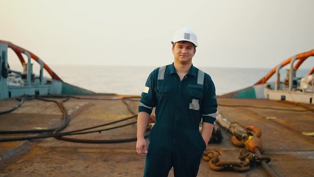 Marine Deck Officer or Chief mate on deck of offshore vessel or ship , wearing PPE personal protective equipment - helmet, coverall. He is looking at the camera