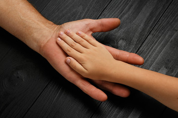 Fototapeta premium Hands of an elderly man holding the hand of child
