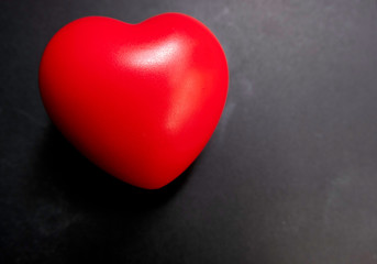 Obraz premium Top view. The red heart on a black background with white light shines down to the heart.