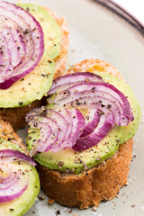 Sandwich with fresh avocado and onion on a plate