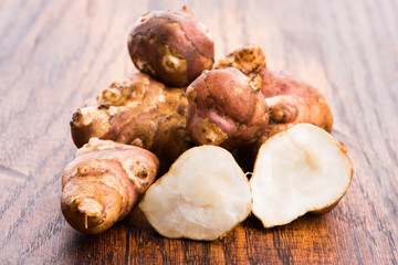 Raw Whole ans sliced Jerusalem artichokes on a cutting board