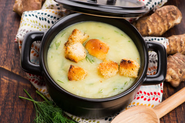 Creamy Jerusalem artichoke soup on wooden background