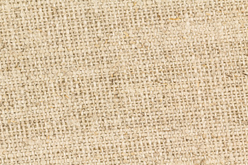 Close up background of coarsely woven jute threads in tan burlap fabric. AKA Hessian cloth.