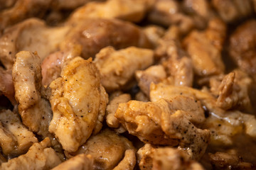 Marinated torn cut chicken bits being cooked, halfway cooked. Spicy chicken, wooden spatula