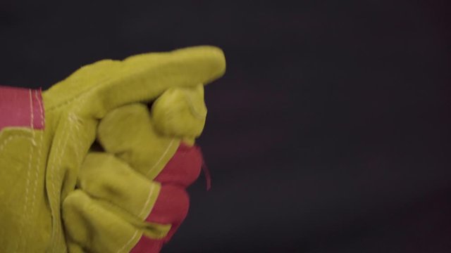 Wear work gloves. Hand of a man close-up on a dark background. Big working new gloves made of rough suede. Special Welder Gloves.