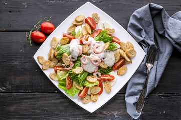 Appetizing salad with shrimp, lettuce, cheese, avocado and crackers on a white plate. Delicious and healthy seafood recipes. Low calories. Top view