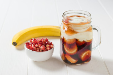 Banana slices in pomegranate juice with yogurt on a white table.