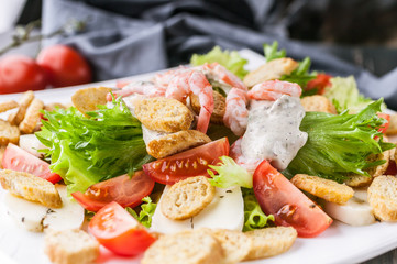 Close-up appetizing salad with shrimp, lettuce, cheese, avocado and crackers on a white plate. Delicious and healthy seafood recipes. Low calories