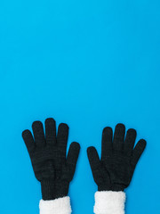 Knitted black women's gloves bottom blue background. The concept of hope and meeting.