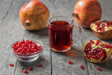 Ripe pomegranate fruit and fresh pomegranate juice on a wooden table.
