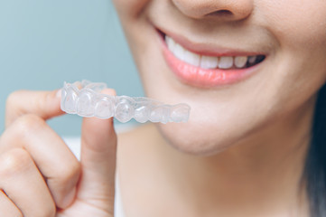close up mouth of Woman holding orthodontic silicone. Mobile orthodontic appliance for dental correction.