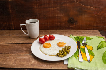 Two fried eggs with a green pot and tomatoes for a healthy breakfast.