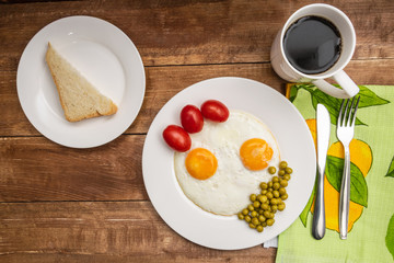 Two fried eggs with a green pot and tomatoes for a healthy breakfast.