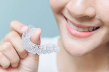 close up mouth of Woman holding orthodontic silicone. Mobile orthodontic appliance for dental correction.