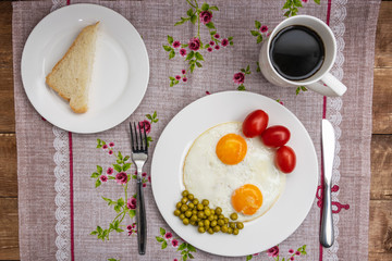 Two fried eggs with a green pot and tomatoes for a healthy breakfast.