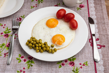 Two fried eggs with a green pot and tomatoes for a healthy breakfast.