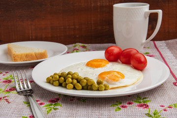 Two fried eggs with a green pot and tomatoes for a healthy breakfast.