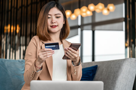 Portrait Asian Woman Using Credit Card With Mobile Phone, Laptop For Online Shopping In Modern Lobby Or Working Space, Coffee Cup, Technology Money Wallet And Online Payment Concept,credit Card Mockup