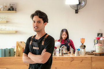 Portrait of a smiling young Asian male entrepreneur standing with her arms crossed