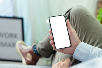 Mockup image blank white screen cell phone.men hand holding texting using mobile on desk at home office. background empty space for advertise text.people contact marketing business and technology 
